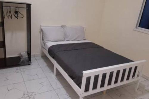 ein weißes Bett in einem weißen Zimmer mit einer schwarzen Matratze in der Unterkunft Bambino Guest House in Brikama