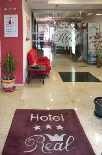 a hotel room lobby with a red chair and a rug at Hotel Real in Plovdiv