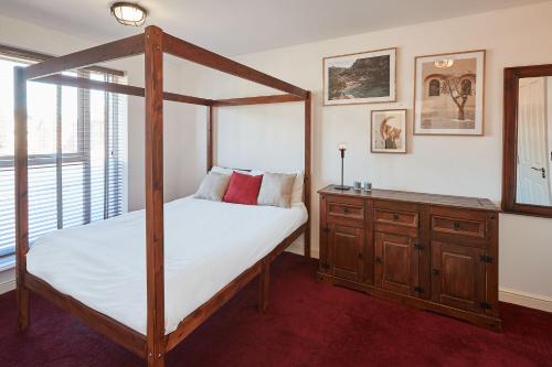 a bedroom with a four poster bed and a wooden dresser at Host & Stay - Greenfinch Road in Coventry