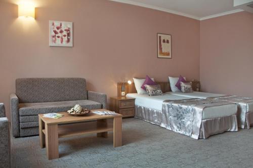 a bedroom with a bed and a chair and a table at Hotel Real in Plovdiv