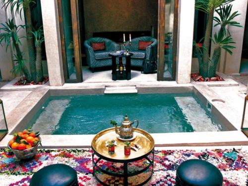 uma piscina com uma mesa e um quarto com um sofá em Riad Vanilla Sma & Spa em Marraquexe
