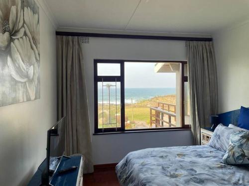 a bedroom with a bed and a view of the ocean at The Beach House in Port Shepstone