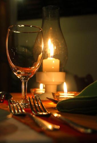 a glass of wine sitting on a table with candles at Athulya Villas, Kandy in Kadugannawa