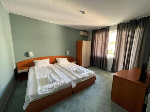 1 dormitorio con 1 cama grande con sábanas blancas en Family Hotel Saga, en Ravda