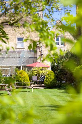 a garden with a table and an umbrella in front of a building at Garden House Stamford in Stamford