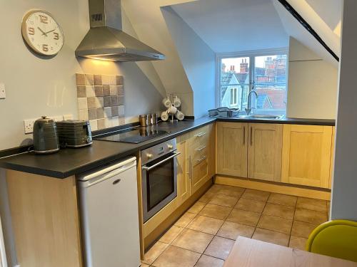 a kitchen with wooden cabinets and a clock on the wall at Elizabeth Clark in Manningtree