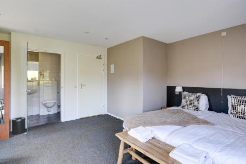 a bedroom with a large bed and a bathroom at Herberg de Loohoeve in Schoonloo