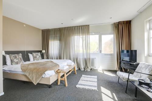 a bedroom with a bed and a tv and a couch at Herberg de Loohoeve in Schoonloo