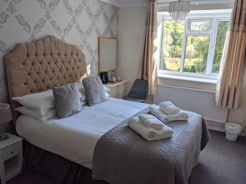 a bedroom with a large bed with towels on it at The Paddocks Hotel in Symonds Yat