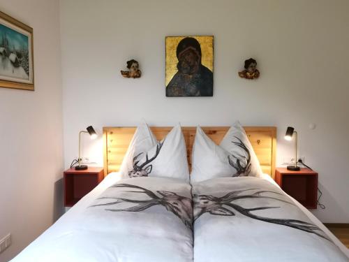 a bedroom with a white bed with a painting on the wall at TYROL PURElife Lodges in Sankt Jakob in Defereggen
