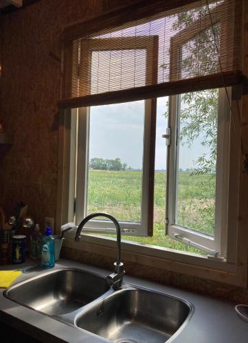 a kitchen sink with a window with a view of a field at Vakantiehuisje De Waddenuil in Usquert