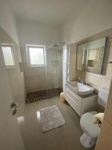 Baño blanco con lavabo y aseo en Apartman Ana en Dobropoljana