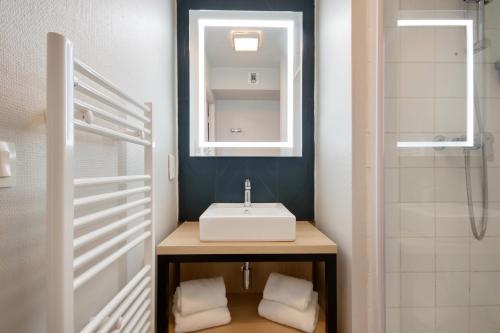 a bathroom with a sink and a mirror at Appart'City Confort Lille Grand Palais in Lille