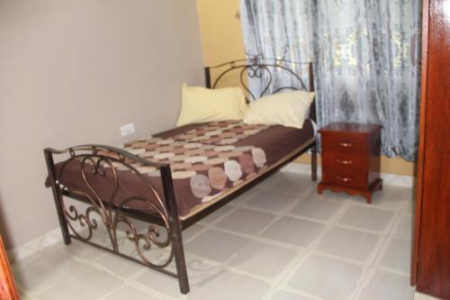 ein kleines Bett in einem Zimmer mit Vorhang in der Unterkunft Snow Valley Cottages in Kasese