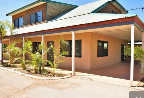 a house with palm trees in front of it at The Ningaloo breeze villa 5 in Exmouth
