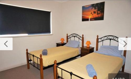 two beds in a room with a chalkboard at The Ningaloo breeze villa 5 in Exmouth