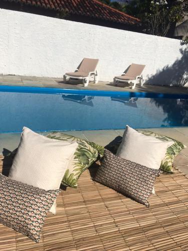 a row of lounge chairs next to a swimming pool at Céu Azul Pousada in Arraial d'Ajuda