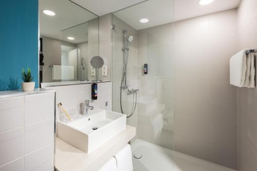 a white bathroom with a sink and a shower at the niu Seven in Düsseldorf