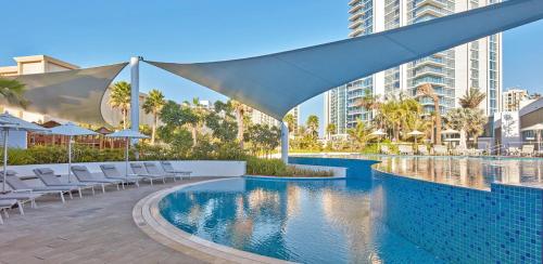 a swimming pool with chairs and a building at Studio with City Views, Jumeirah Lake Towers - Mint Stay in Dubai