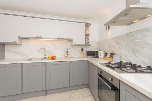 a white kitchen with white cabinets and a stove at Crescent Mews in Bath