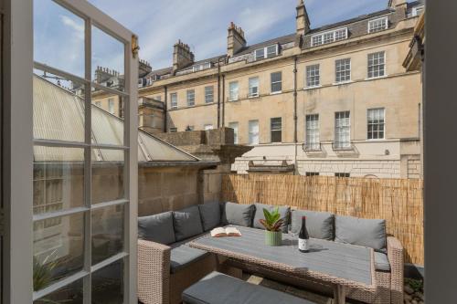 a patio with a couch and a table on a balcony at Crescent Mews in Bath