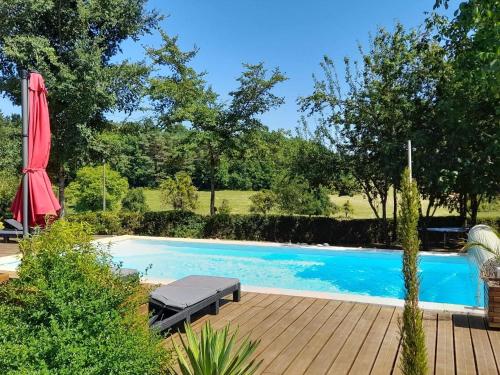 einen Pool mit einer Terrasse und einem roten Regenschirm in der Unterkunft Le Petit Coin - LPC Dordogne Holidays in Lussas-et-Nontronneau