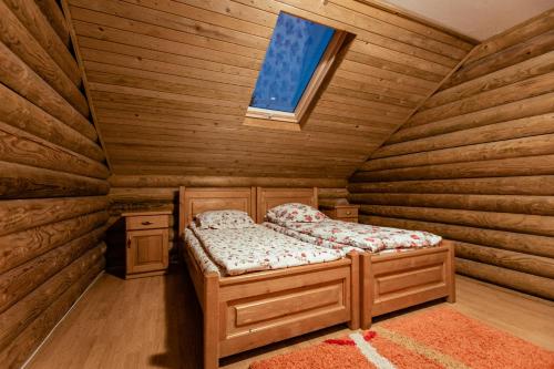 małe łóżko w drewnianym pokoju z oknem w obiekcie Cabana La Panţiru w mieście Văleni-Stînişoara