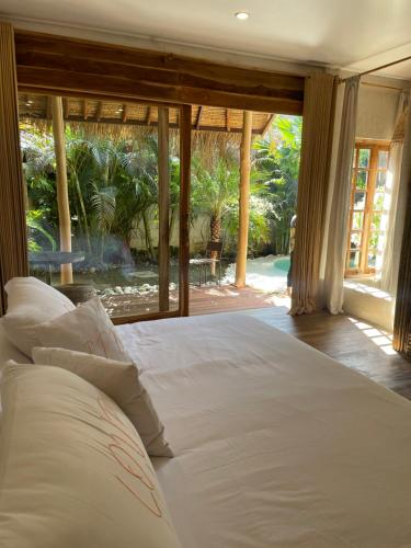 a large bed in a room with a large window at La Cabane in Jimbaran