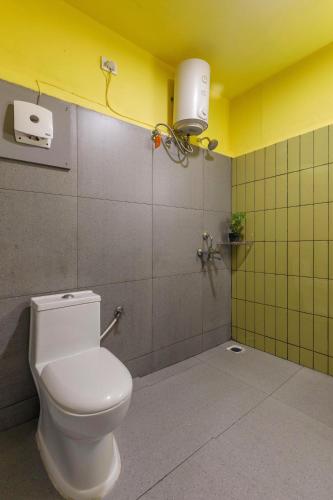 a bathroom with a toilet and a yellow wall at Locul Midtown-Indiranagar in Bengaluru