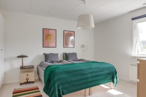 um quarto com uma cama com um cobertor verde em Family home near the ocean, with large patio & BBQ em Skärhamn