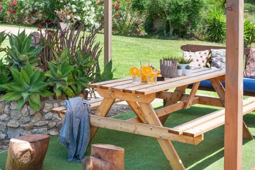 a wooden picnic table with drinks on it in a garden at Villa Lucas in Pollença