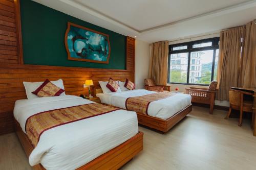 um quarto de hotel com duas camas e uma janela em Hotel Tulsi em Pokhara