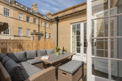 a patio with a couch and a table on a balcony at Crescent Mews in Bath