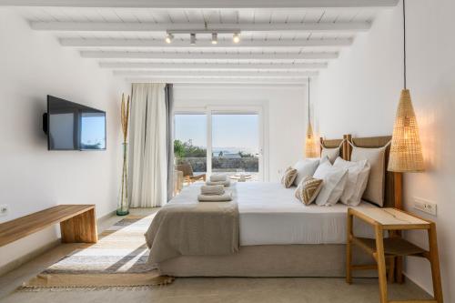 a white bedroom with a large bed and a television at Mykonos Lagom in Mikonos