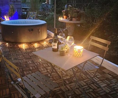 a table with wine glasses and a tub with lights at Superbe appartement avec jacuzzi avec jardin privé in Lyon