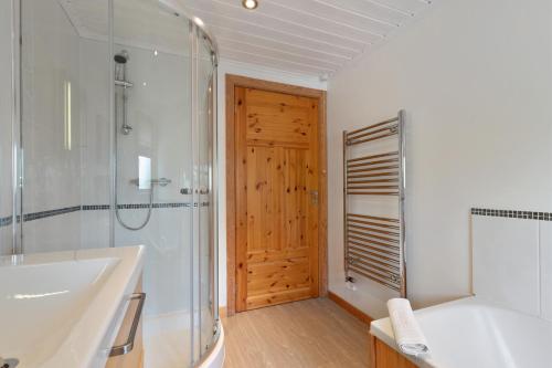 a bathroom with a tub and a shower and a sink at The Bluebell - Luxury Lodge with Hot Tub in Penally