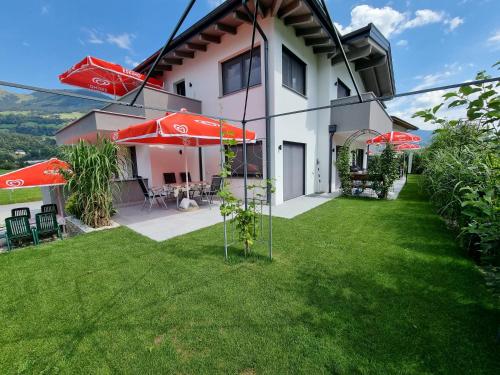 a house with red umbrellas in a yard at Golf & Ski Appartements Mittersill Trausmuth Monika inkl Sommercard - Golfplatz 500 m entfernt, inkl Waschmaschine, Trockner in Mittersill
