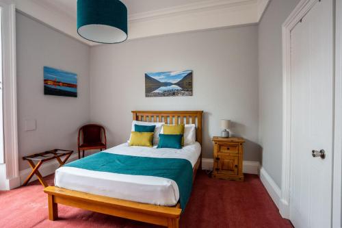 a bedroom with a bed with blue and yellow pillows at The Juniper Rooms in Montrose