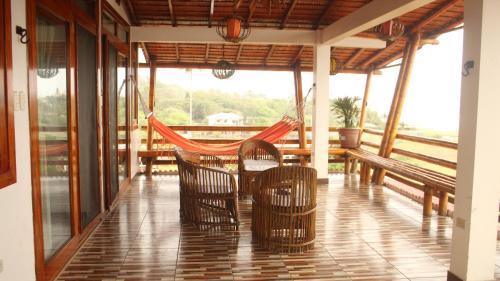 un porche con hamaca, mesas y bancos en Hotel Sotavento en Montañita