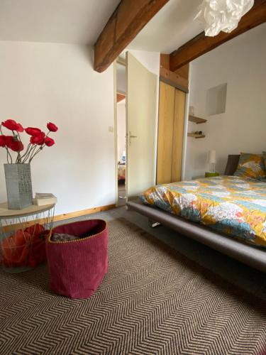 1 dormitorio con 1 cama y un jarrón con flores rojas en Duplex Arago au coeur de Sète, comme une petite maison, en Sète