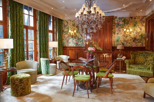 ein Wohnzimmer mit einem Tisch, Stühlen und einem Kronleuchter in der Unterkunft Hotel Estheréa in Amsterdam