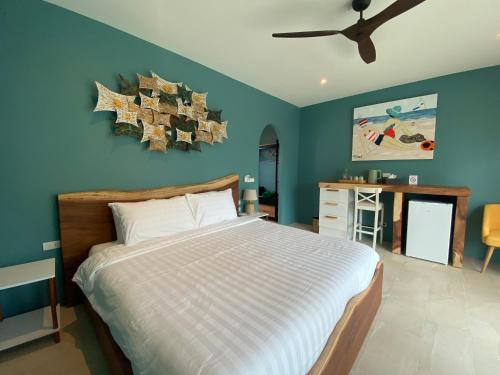 ein Schlafzimmer mit einem großen Bett und einer blauen Wand in der Unterkunft Le Petit Saint Tropez in Khanom