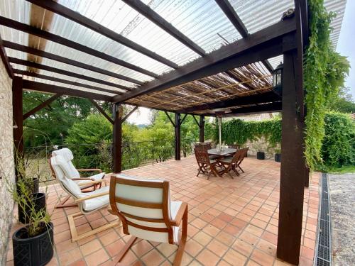 a wooden pergola with chairs and a table on a patio at Anahata Gite in Constant