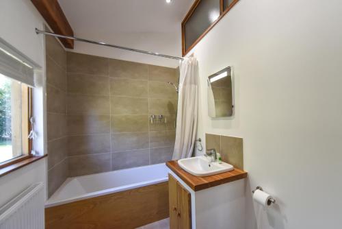 ein Bad mit einer Badewanne, einem Waschbecken und einer Dusche in der Unterkunft Amber Cabin in Ashover