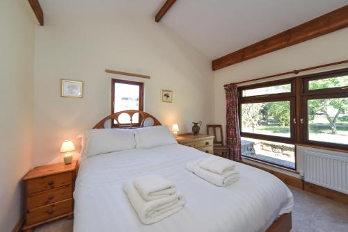 a bedroom with a white bed with two towels on it at Amber Cabin in Ashover