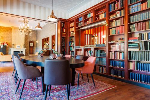 a library with a table and chairs and bookshelves at Bastion Hotel Apeldoorn Het Loo in Apeldoorn