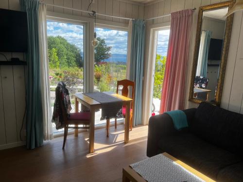 een woonkamer met een tafel en een groot raam bij Fantastisk Vätterutsikt mellan Habo och Bankeryd. in Habo