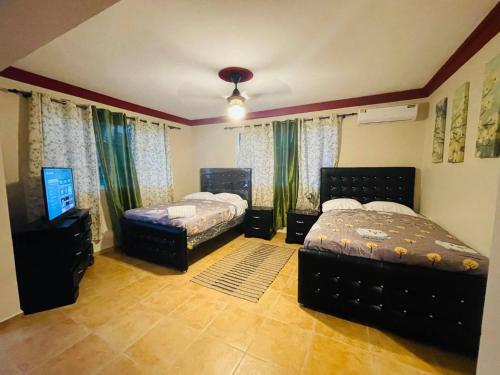 a bedroom with two beds and a flat screen tv at Lovely 2 Bedroom Condo With Pool And Hot Water in Cabarete