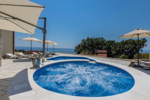 a large blue pool with umbrellas on a patio at Villa La Residenza - Heated pool in Podstrana