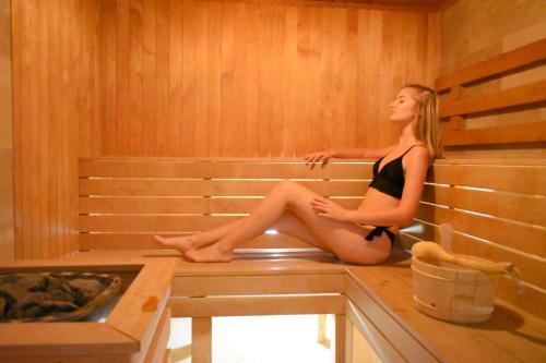 a woman is sitting in a sauna at Tisza Balneum Hotel in Tiszafüred